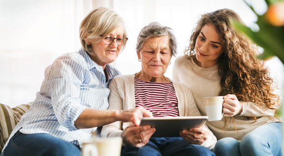 Women of three generations discussing around a handheld tablet