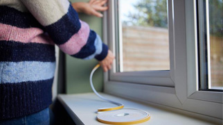 woman putting draught excluder up at window