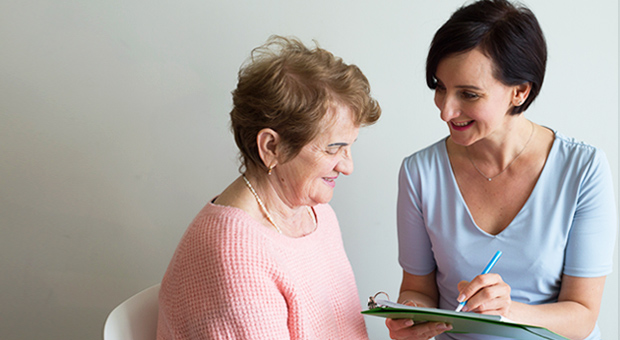 older woman talking to a woman filling in an assessment form 