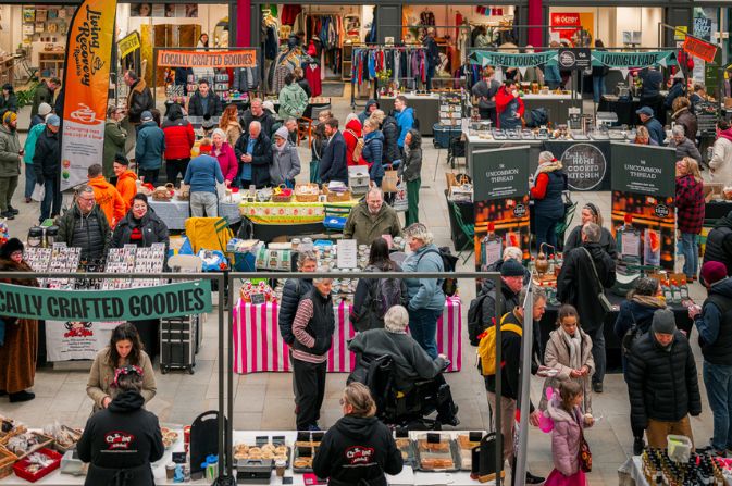 Crowds of people browse the stalls at a farmers market inside Derby Market Hall