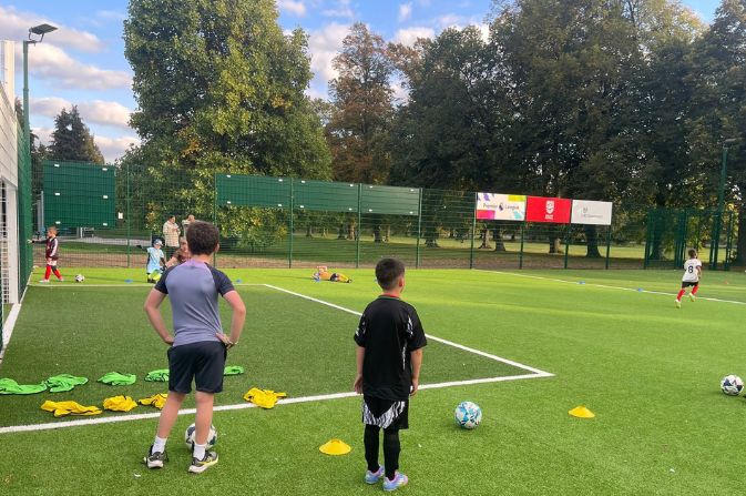 A group of children football training on a bright green PlayZone pitch