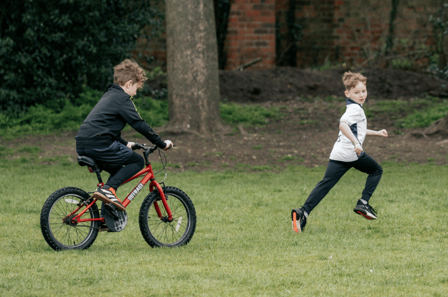 child riding a bike and another child running