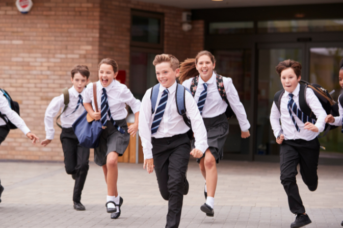 Several children in school uniform run towards the camera