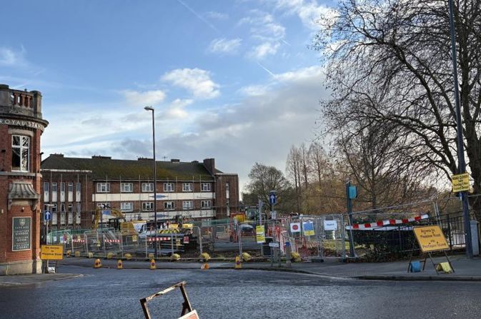 A construction site in front of a small apartment building.