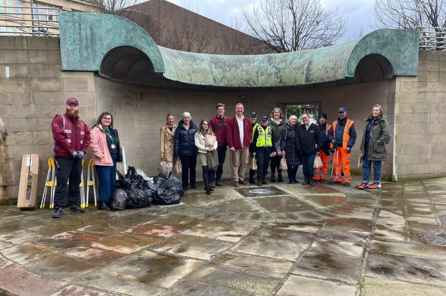 volunteers by the Market Place fountain with a pile of black bin bags filled with rubbish