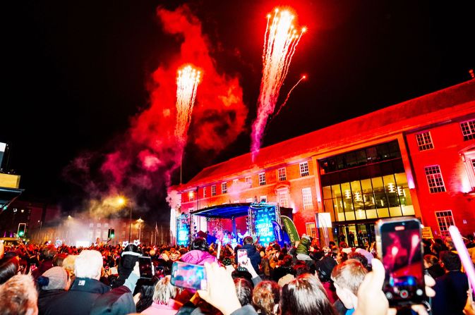 A crowd gathered in front of a stage as pyrotechnics light up the sky at the moment Derby's Christmas lights are switched on.