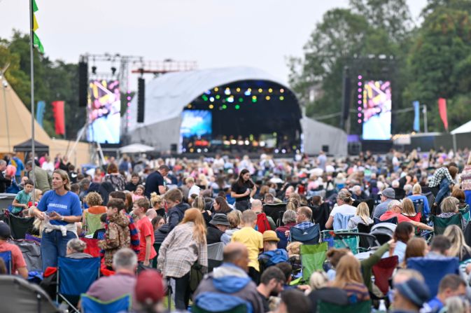 Large crowd sat looking at an outdoor stage.