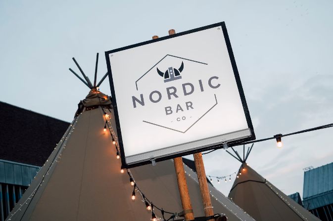 Sign for the Nordic Bar set against the teepee peaks and fairy lights