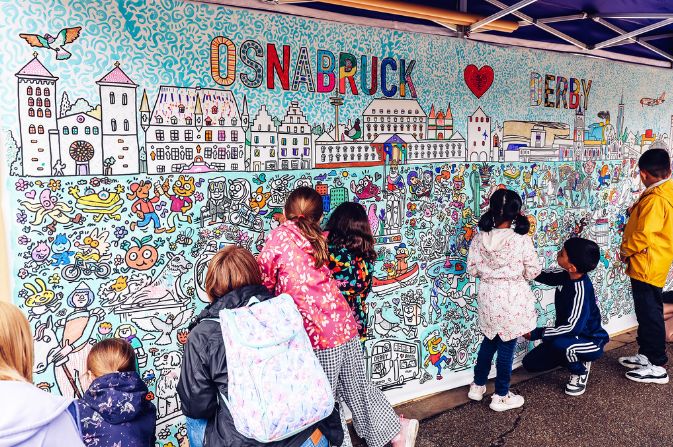 Children colouring in a huge doodle depicting Derby and Osnabruck