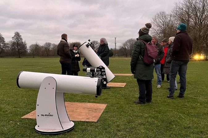 A group of people gather at Alvaston Park, with two large telescopes, for the stargazing event