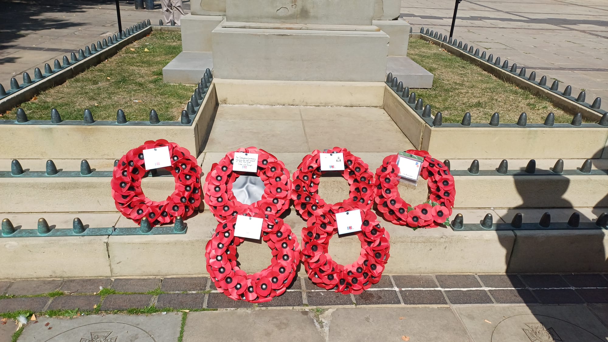 Five red poppy wreaths on a stone step.