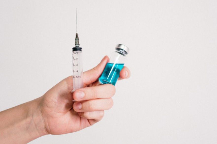 Hand holding syringe and vaccine
