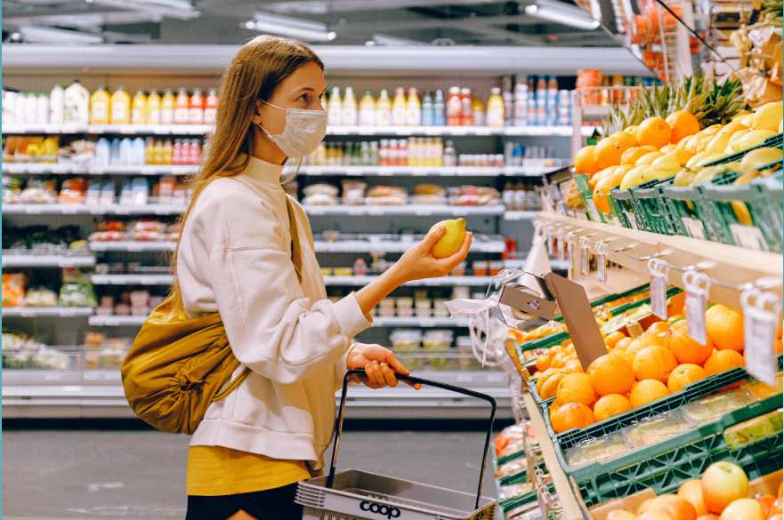 Woman shopping and holding fruit in mask