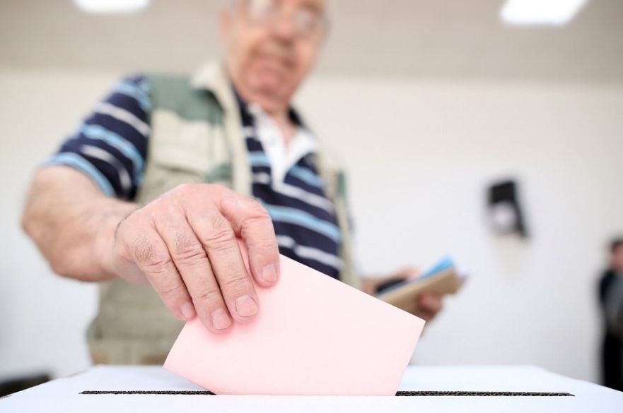 man putting ballot slip in ballot box