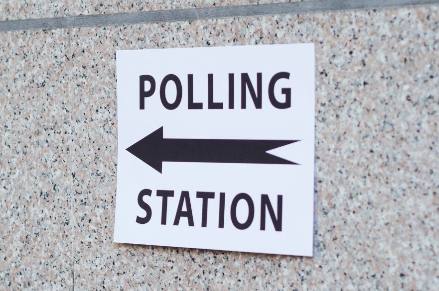 polling station sign with direction on wall.