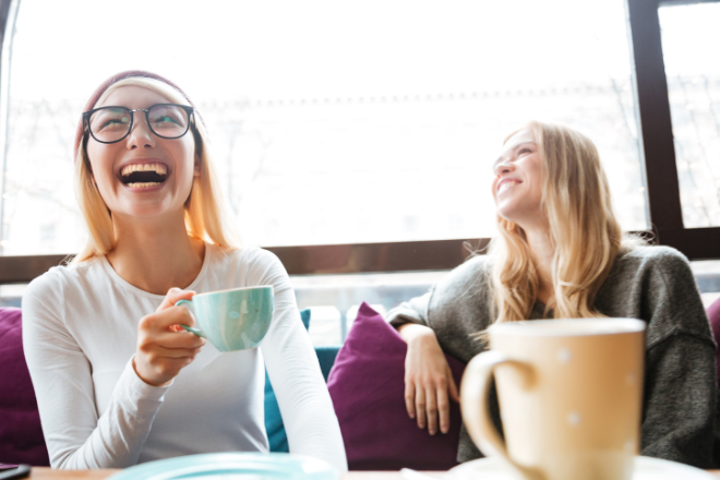 Two young people sit in a cafe laughing