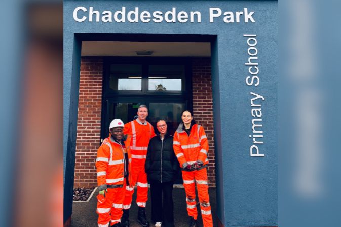 A group of people in high visibility clothing in the doorway of Chaddesden Park Primary School.