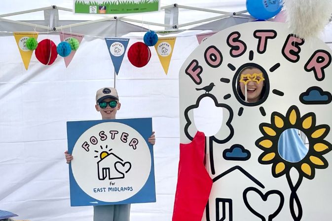 Boy holding a board for Foster for East Midlands, wearing a hat and sunglasses.