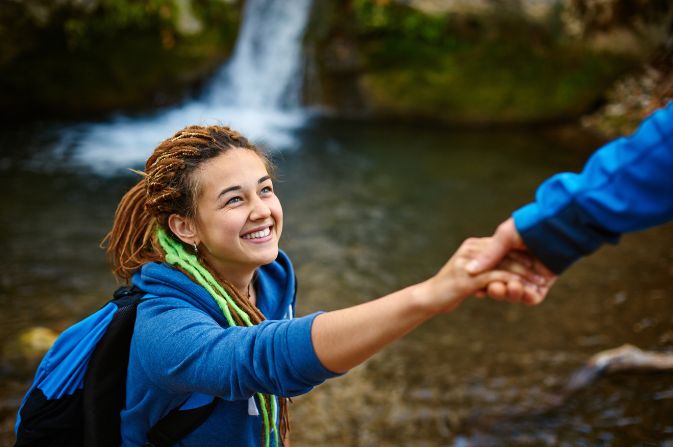 A teenage girl climbing given a helping hand