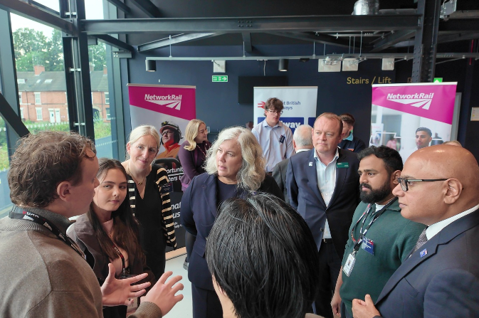 Group discussion at a rail careers event, with attendees gathered beside Network Rail and Great British Railways apprenticeship banners.