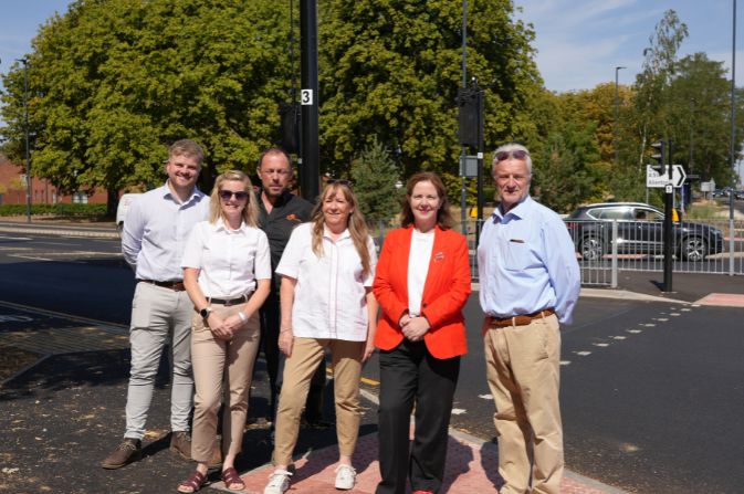A group of people stood for a photo by a road junction.