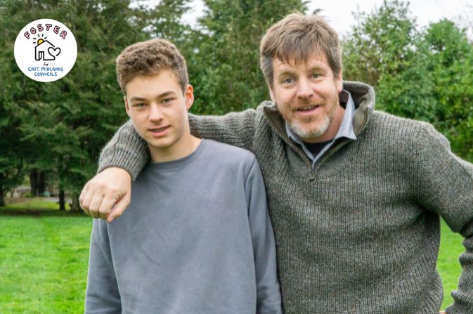 Man and older boy teenager in a green field with trees