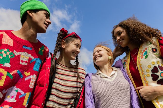 Four smiling young people chat to one another