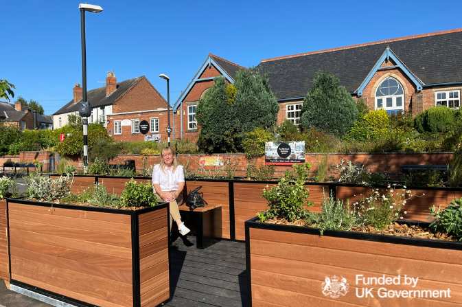 Cllr Swan sat on a bench at the Etwall Road pocket park